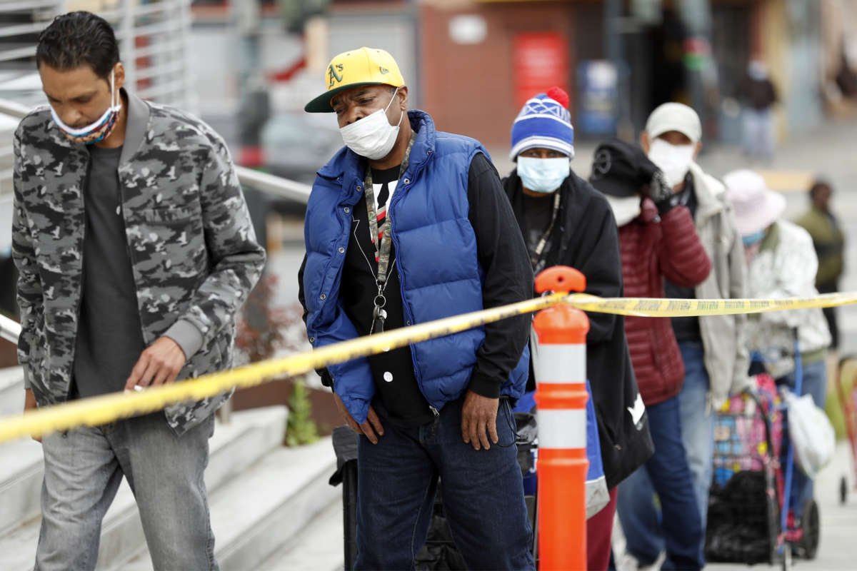 Masked people wait in a line for food