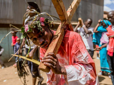 A bloodied man carries a cross