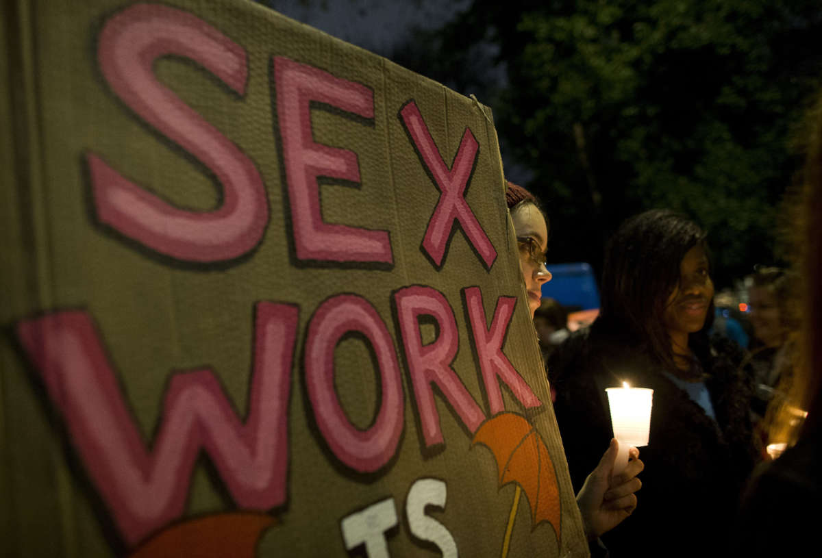 A protester holds a placard during a candle lit vigil to mark the International Day to End Violence Against Sex Workers in London on December 17, 2014.