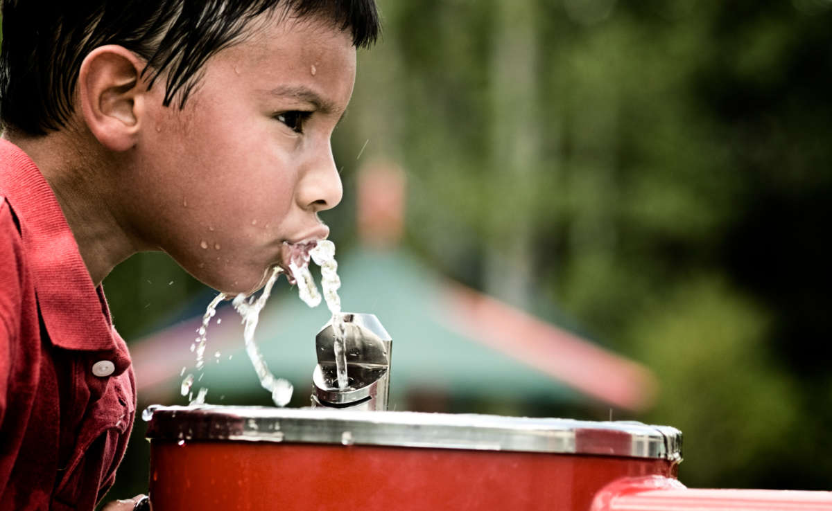 A child drinks water from a fountain