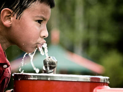 A child drinks water from a fountain