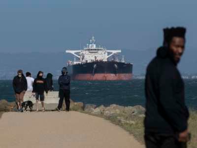 People enjoy sunshine as an oil tanker is berthed at San Francisco Bay amid the coronavirus outbreak on April 26, 2020, in San Francisco, California.