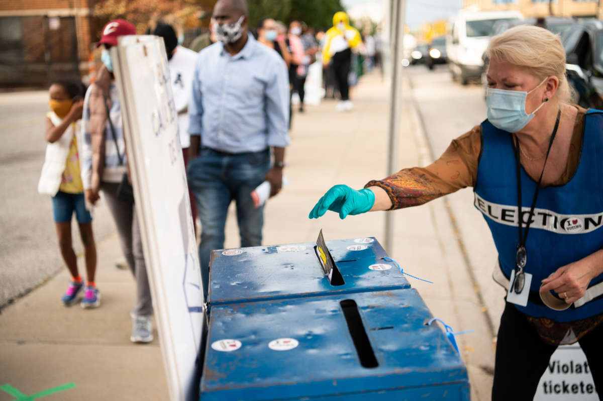 A lady drops a ballot into a ballot box