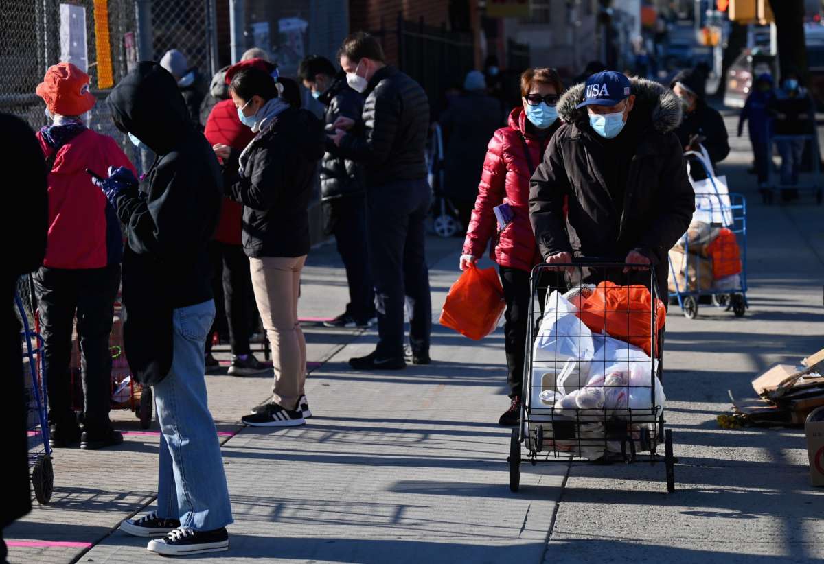 People stand in line at a food distribution event ahead of the Thanksgiving holiday on November 20, 2020, in the Brooklyn borough of New York City.