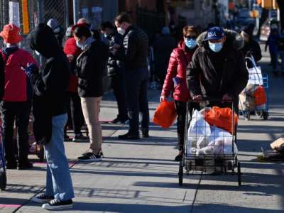 People stand in line at a food distribution event ahead of the Thanksgiving holiday on November 20, 2020, in the Brooklyn borough of New York City.