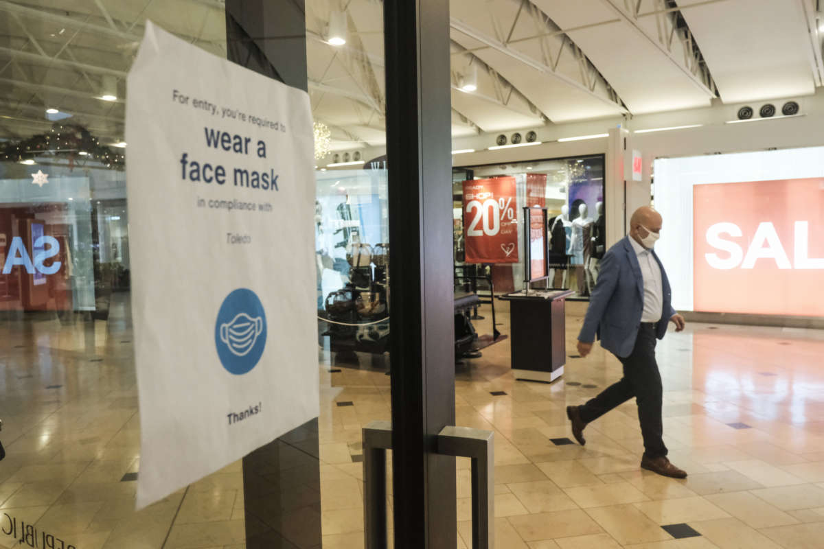 Signs urging social distancing and masks line the windows of most shops at the Franklin Park Mall during the Black Friday sales event on November 27, 2020, in Toledo, Ohio.