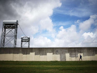 A person walks along the rebuilt Industrial Canal levee wall in the Lower Ninth Ward on May 18, 2015, in New Orleans, Louisiana.