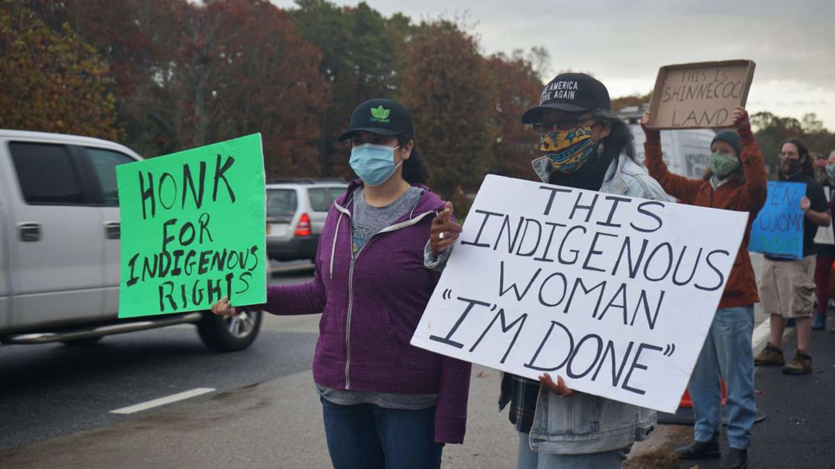 Masked Indigenous activists display signs during a roadside protest