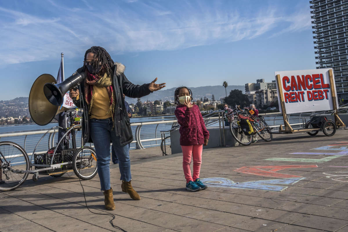 Newly-elected Oakland City Council member Carroll Fife speaks to a rally in Oakland, calling for cancelling rents. Aja, the daughter of Dominique Walker, stands beside her.