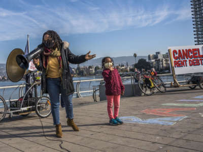 Newly-elected Oakland City Council member Carroll Fife speaks to a rally in Oakland, calling for cancelling rents. Aja, the daughter of Dominique Walker, stands beside her.