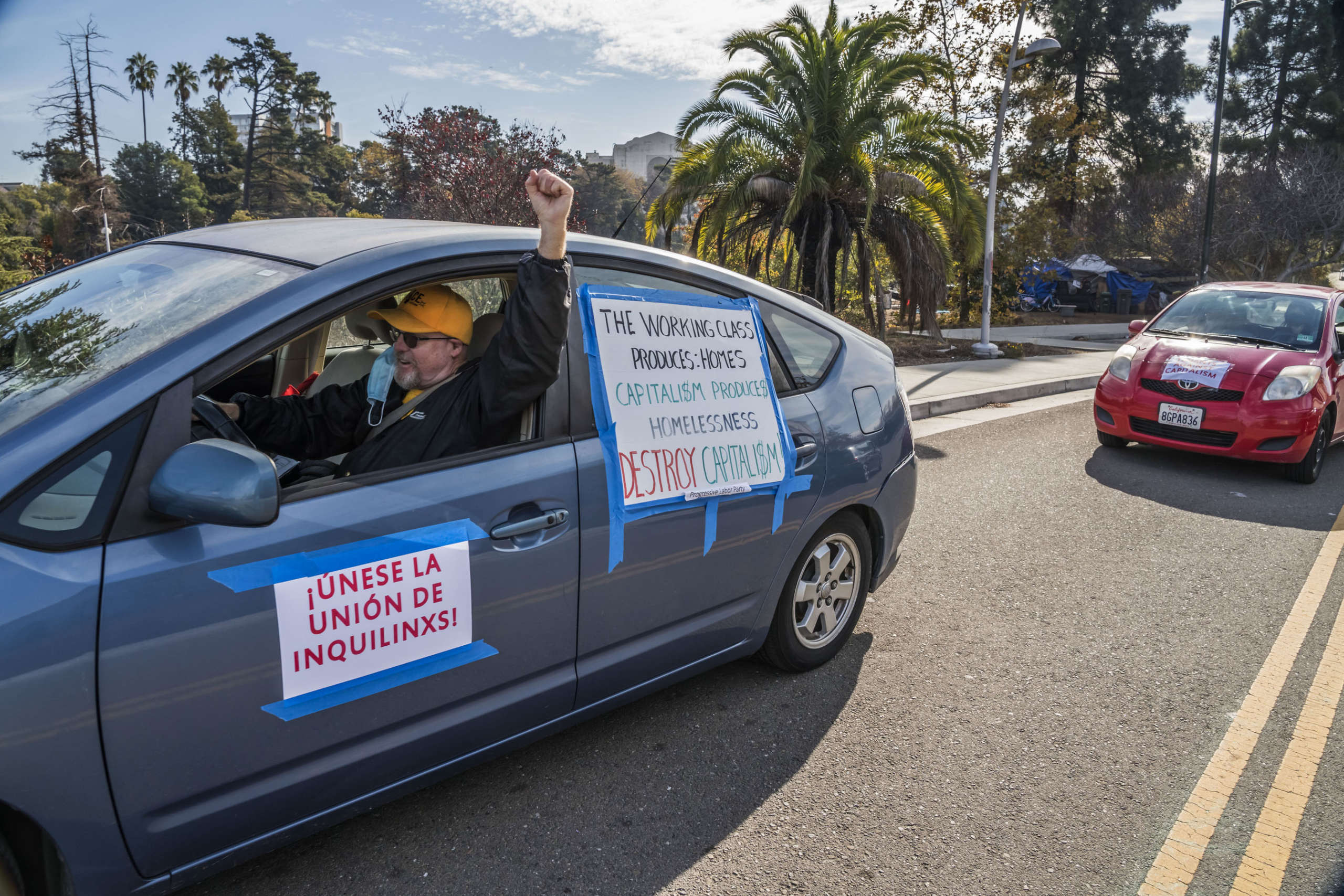A driver holds up his fist in a car with his demands taped to the windows.