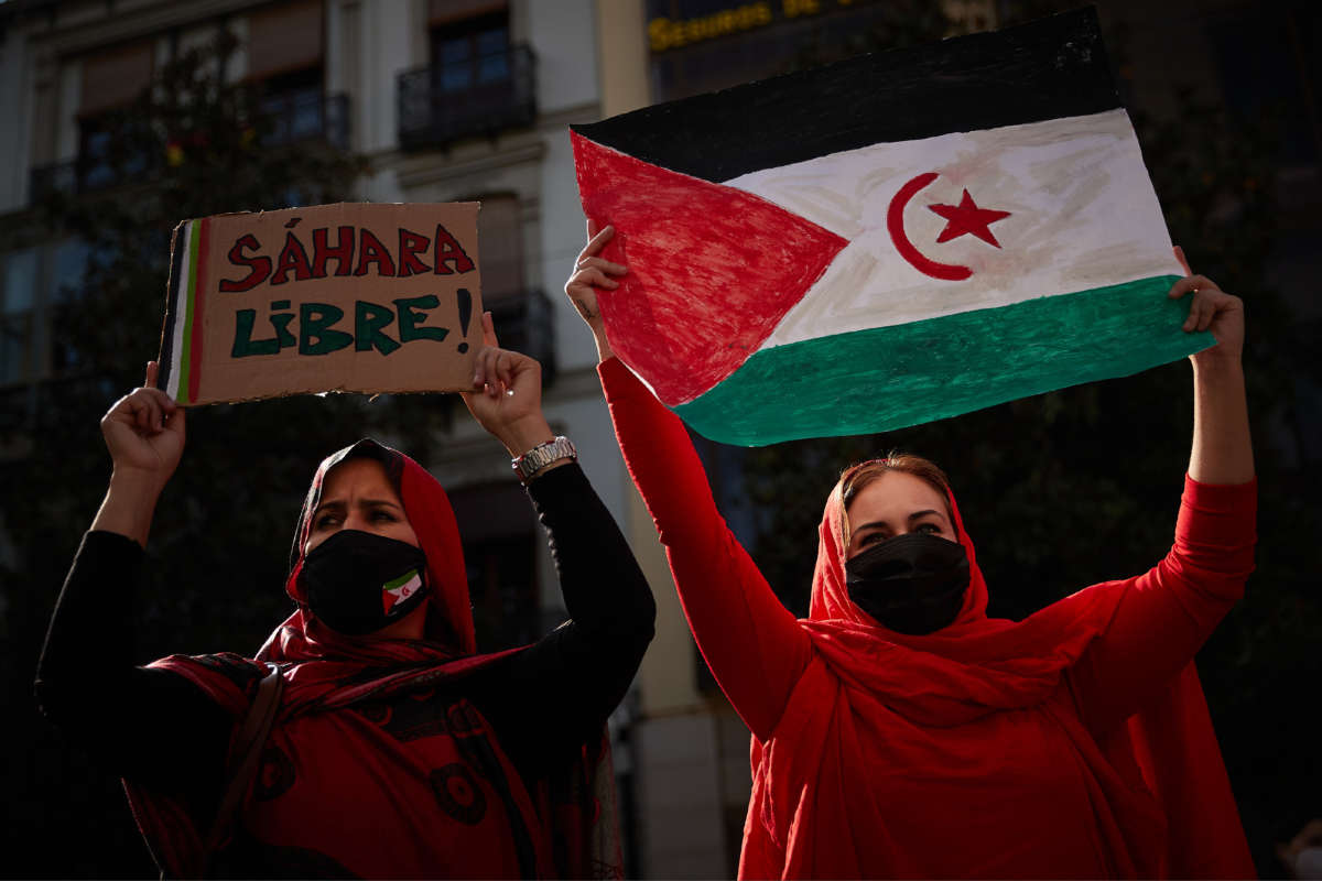 Women wearing face masks carry a Saharan flag and a placard that says Free Sahara during a demonstration to demand the end of Morocco's occupation in Western Sahara on November 21, 2020, in Granada.