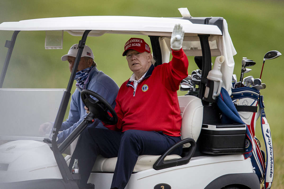 Donald Trump waves from a golf cart