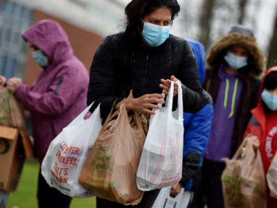 People carry food donated by volunteers from the Baltimore Hunger Project outside of Padonia International Elementary school on December 4, 2020, in Cockeysville, Maryland.