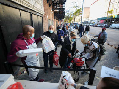 Volunteers from a nonprofit organization provide food supplies to people who line up ahead of Thanksgiving amid the COVID-19 pandemic in Harlem of New York City on November 20, 2020.