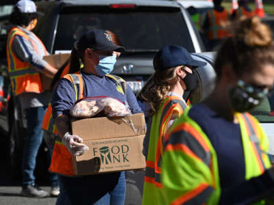 Volunteers load free groceries into cars for people experiencing food insecurity due to the coronavirus pandemic, December 1, 2020, in Los Angeles, California.