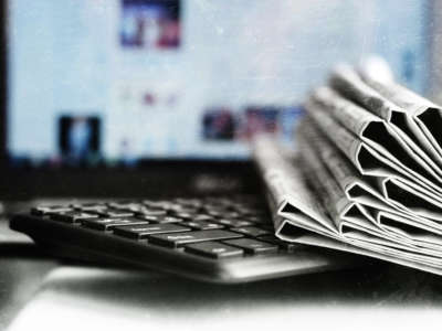 A stack of newspapers by a computer and keyboard