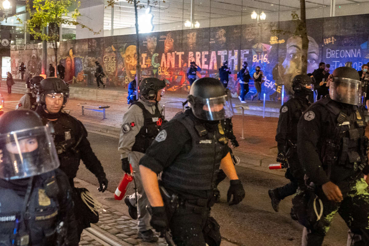 Portland police disperse a crowd of protesters past a mural of George Floyd and Breonna Taylor on September 26, 2020, in Portland, Oregon.