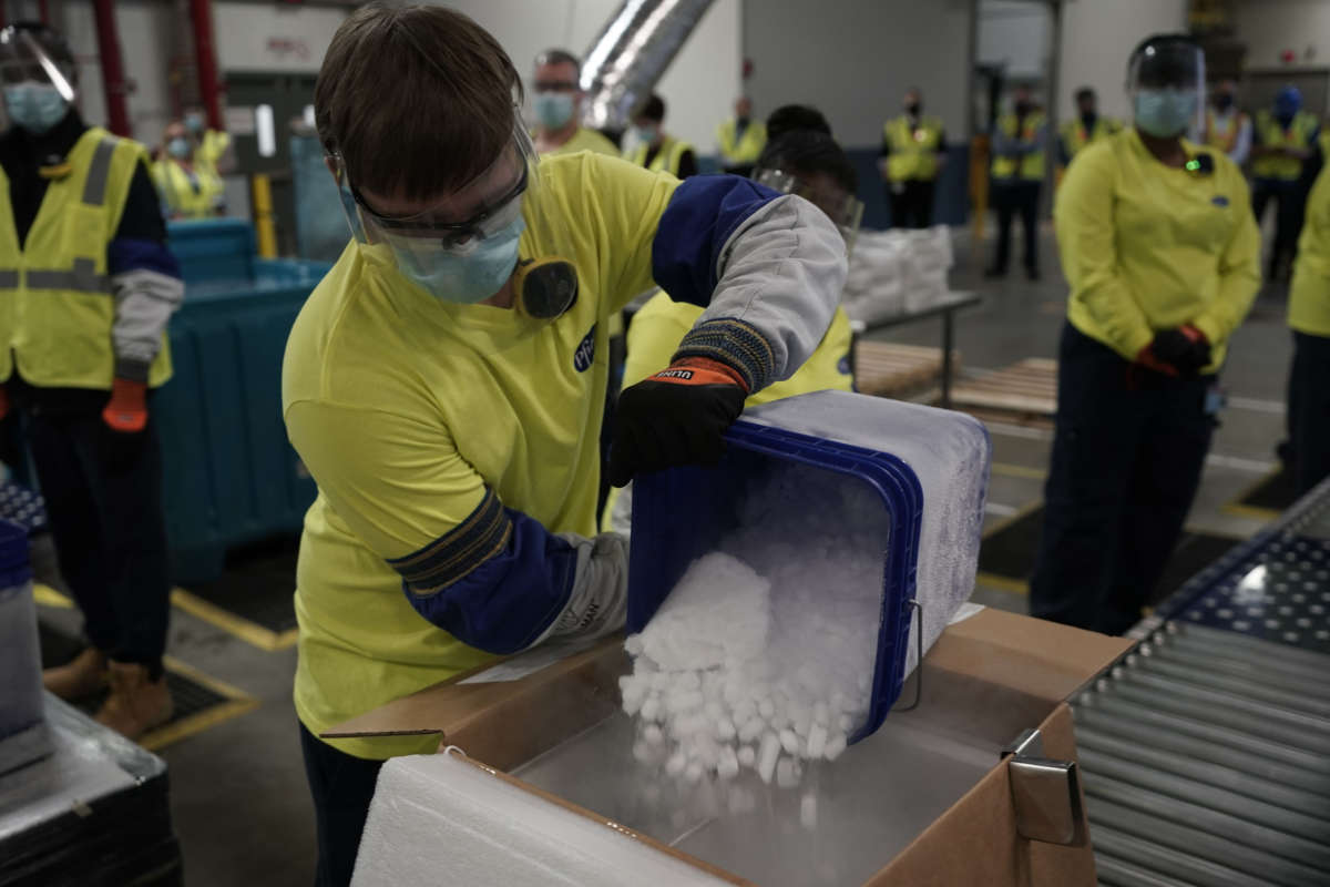 A worker pours dry ice into boxes containing the Pfizer-BioNTech Covid-19 vaccine as they are prepared to be shipped at the Pfizer Global Supply Kalamazoo manufacturing plant in Kalamazoo, Michigan, on December 13, 2020.