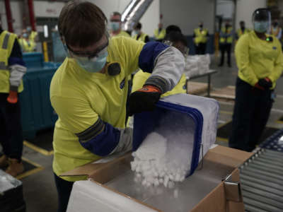 A worker pours dry ice into boxes containing the Pfizer-BioNTech Covid-19 vaccine as they are prepared to be shipped at the Pfizer Global Supply Kalamazoo manufacturing plant in Kalamazoo, Michigan, on December 13, 2020.