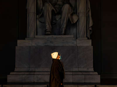 A woman stands in a beam of sunlight streaming into the Lincoln Memorial as the sun rises on December 27, 2020, in Washington, D.C.