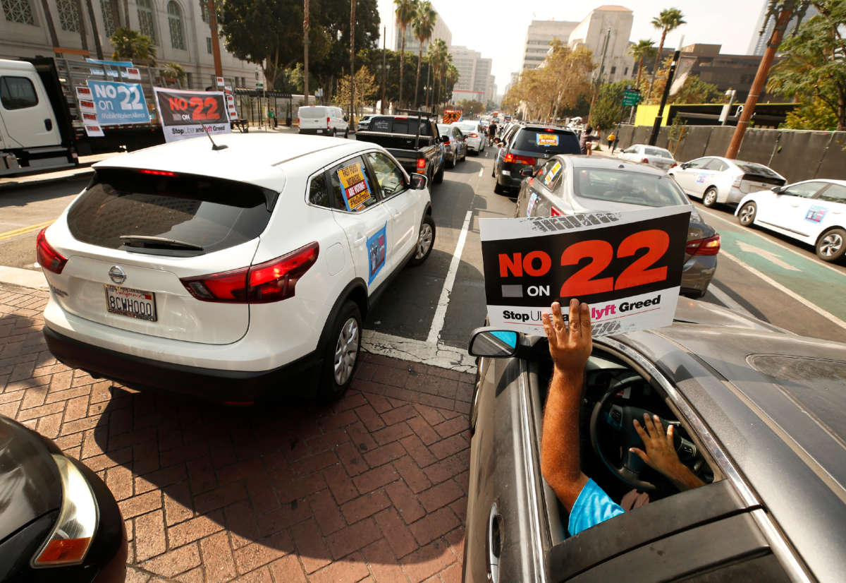 Rideshare driver Jorge Vargas raises his "No on 22" sign in support as app-based gig workers hold a driving demonstration with 60-70 vehicles blocking Spring Street in front of Los Angeles City Hall on October 8, 2020, in Los Angeles, California.