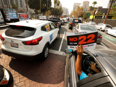 Rideshare driver Jorge Vargas raises his "No on 22" sign in support as app-based gig workers hold a driving demonstration with 60-70 vehicles blocking Spring Street in front of Los Angeles City Hall on October 8, 2020, in Los Angeles, California.