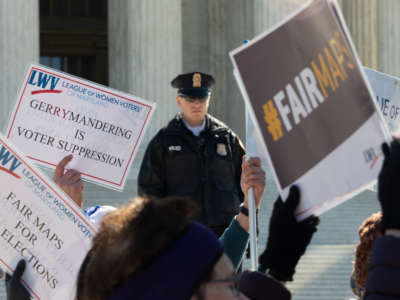 Organizations and individuals gather outside the Supreme Court to protest the manipulation of district lines as a police officer watches on March 26, 2019.