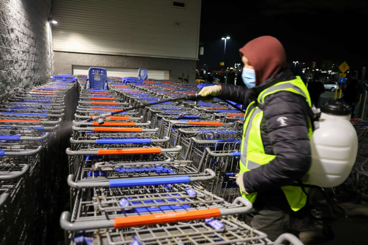 A man sanitizes shopping carts as people line up early morning at Walmart during Black Friday amid the COVID-19 pandemic in New Jersey, on November 27, 2020.