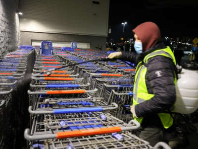 A man sanitizes shopping carts as people line up early morning at Walmart during Black Friday amid the COVID-19 pandemic in New Jersey, on November 27, 2020.