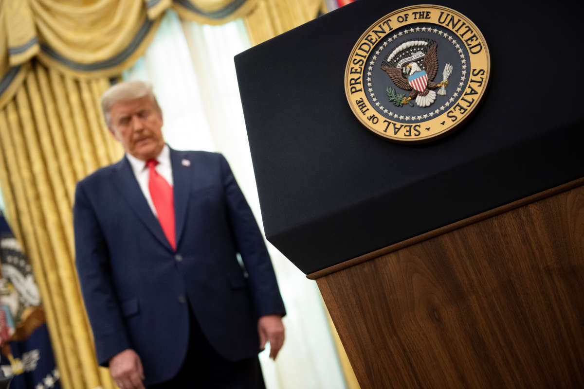 Donald Trump listens during a Medal of Freedom ceremony for retired football Lou Holtz in the Oval Office of the White House December 3, 2020, in Washington, D.C.