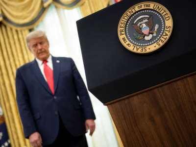 Donald Trump listens during a Medal of Freedom ceremony for retired football Lou Holtz in the Oval Office of the White House December 3, 2020, in Washington, D.C.