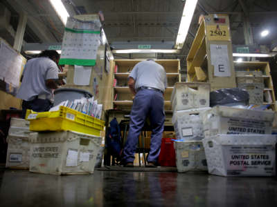 Letter carrier Steve Guerra sorts mail at his station inside the Roxbury Post Office in Nubian Square before heading out to deliver mail and packages in Boston on December 1, 2020.