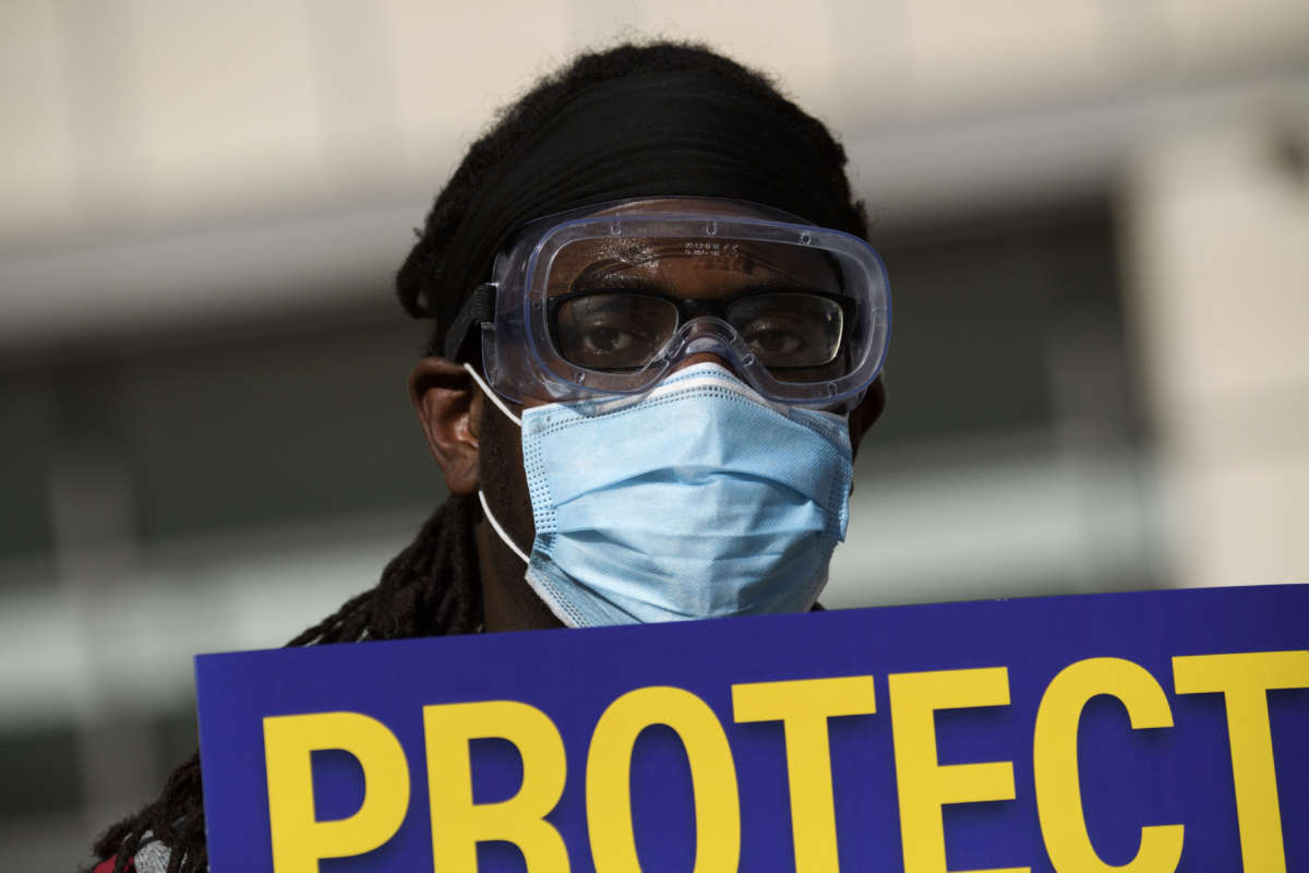 Dr. Salam Beah wears a face mask and carries a sign in support of resident physicians, interns and fellows at UCLA Health as they protest for improved COVID-19 testing and workplace safety policies outside of UCLA Medical Center in Los Angeles, California, December 9, 2020.