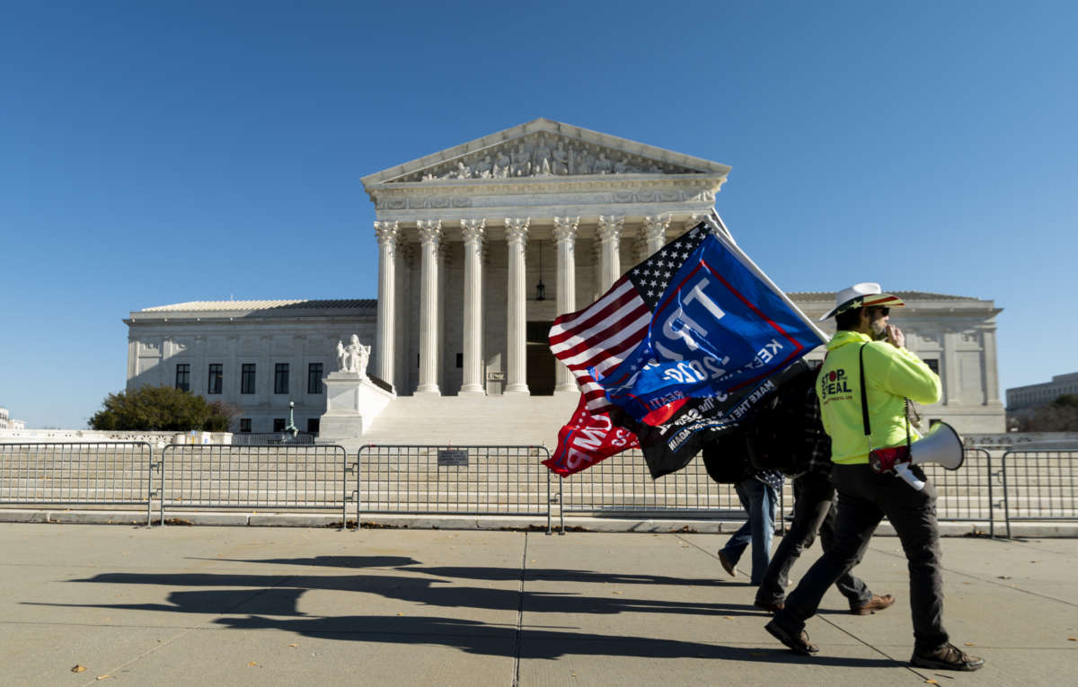 A handful of Trump supporters carry flags in front of the U.S. Supreme Court on December 11, 2020.