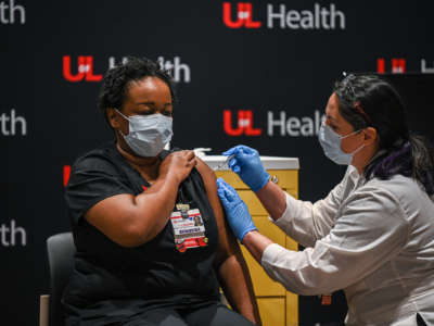 A masked woman is administered with a vaccine