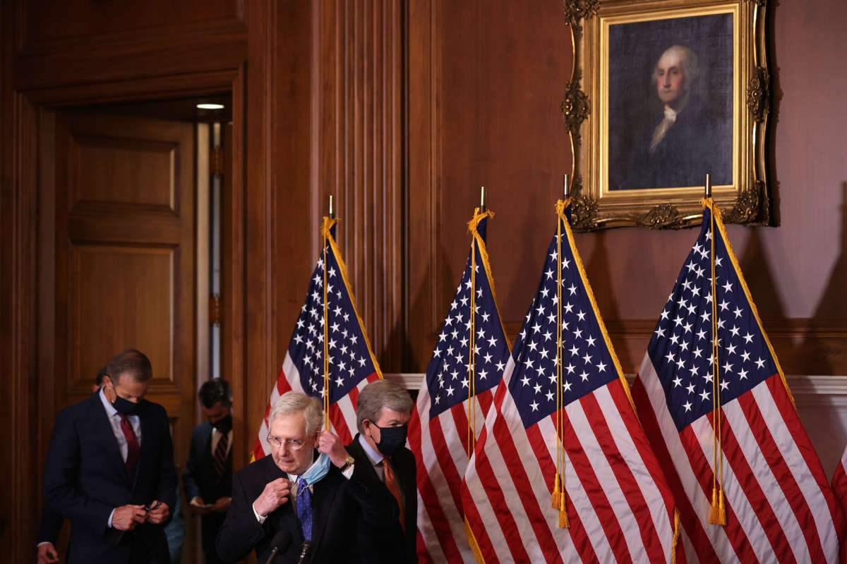 Senate Majority Leader Mitch McConnell removes his face mask as he leads fellow Republican senators into a news conference in the Mansfield Room at the U.S. Capitol on December 1, 2020, in Washington, D.C.
