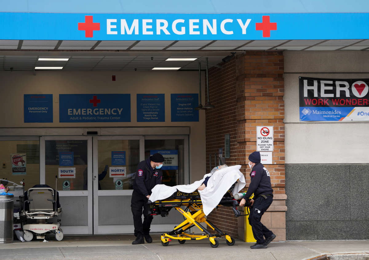 Two paramedics transport a patient through the entrance of an emergency Room