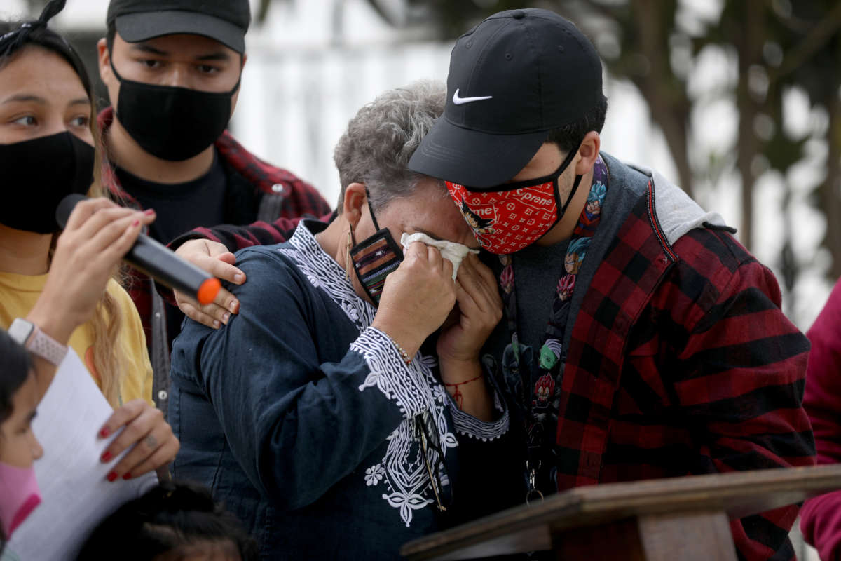 Sonia Alvarez-Zayas, center, is comforted by nephew Alexis Alvarez, 23, while daughter Izzy Ochoa, far left, asks Trojan Capital Investment to not evict them from their house at a press conference held on December 23, 2020, in Inglewood, California.