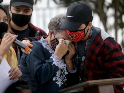 Sonia Alvarez-Zayas, center, is comforted by nephew Alexis Alvarez, 23, while daughter Izzy Ochoa, far left, asks Trojan Capital Investment to not evict them from their house at a press conference held on December 23, 2020, in Inglewood, California.