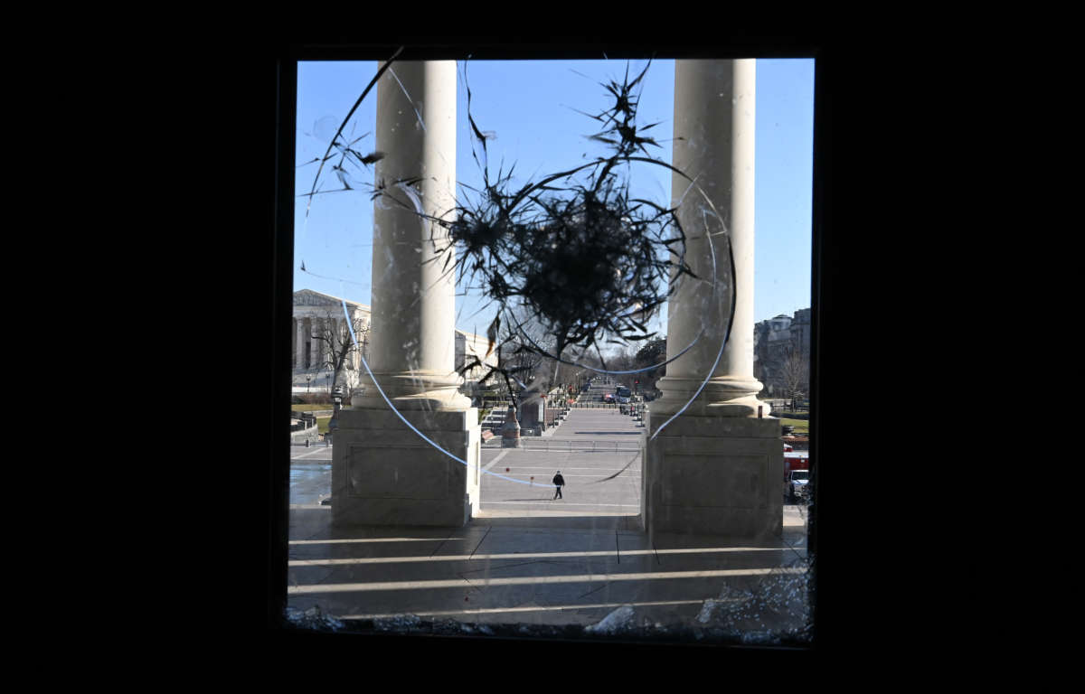 A U.S. Capitol police officer is seen through a broken window of the U.S. Capitol on January 7, 2021, in Washington, D.C.