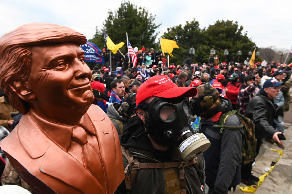 A Trump supporter wears a gas mask and holds a bust of him after hundreds stormed stormed the Capitol building on January 6, 2021, in Washington, D.C.