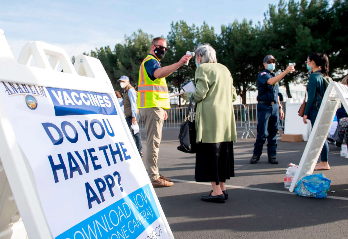 People have their temperature checked as they arrive at a Disneyland parking lot to receive COVID-19 vaccines on the opening day of the Disneyland COVID-19 vaccination "super Point-of-Dispensing" site, January 13, 2021, in Anaheim, California.