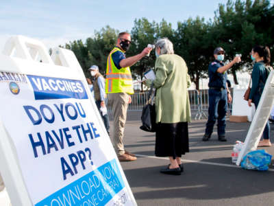 People have their temperature checked as they arrive at a Disneyland parking lot to receive COVID-19 vaccines on the opening day of the Disneyland COVID-19 vaccination "super Point-of-Dispensing" site, January 13, 2021, in Anaheim, California.