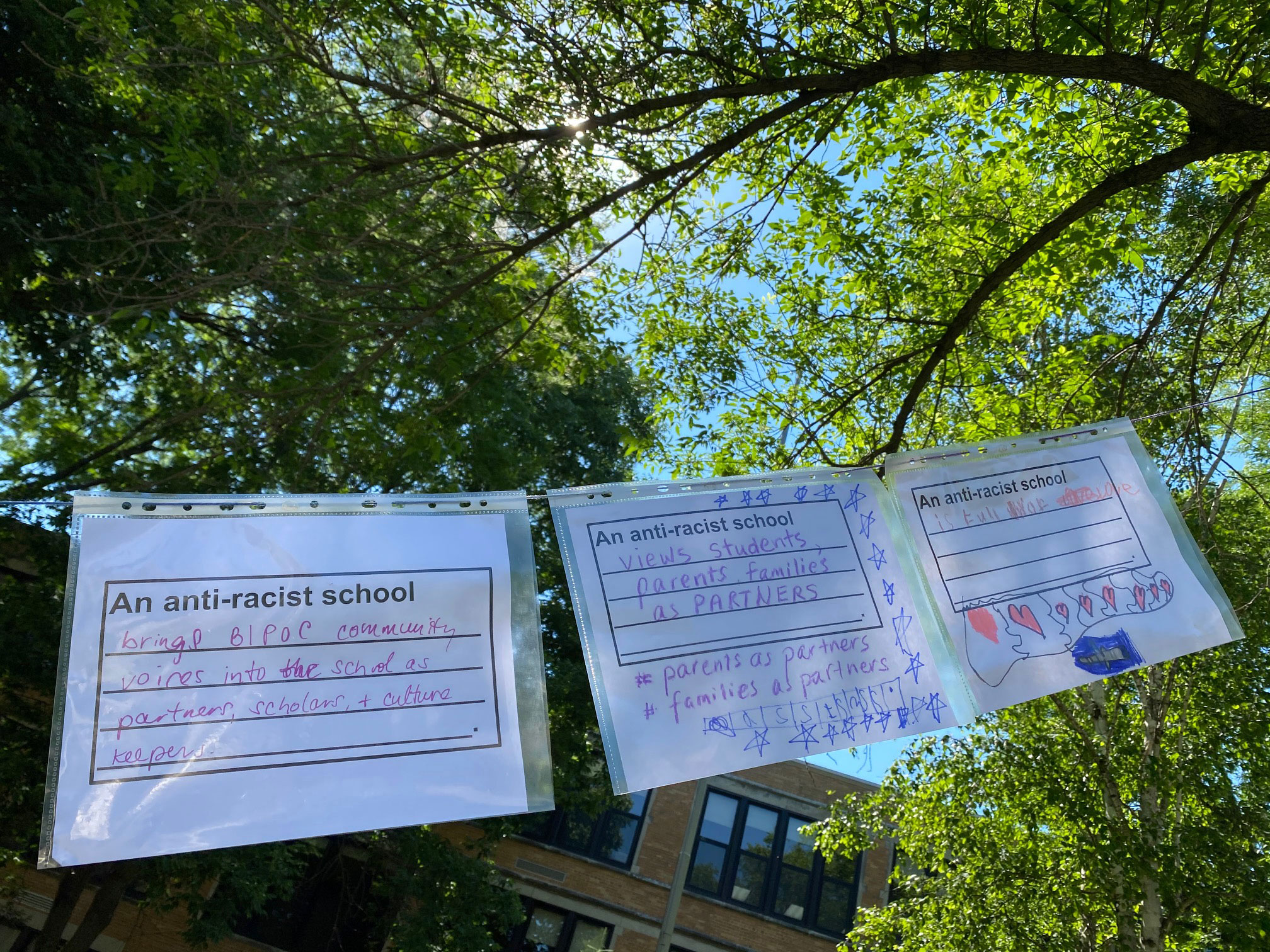 Youth and families’ visions for an antiracist school hang in front of an elementary school during a Day of Solidarity action in Madison, Wisconsin.