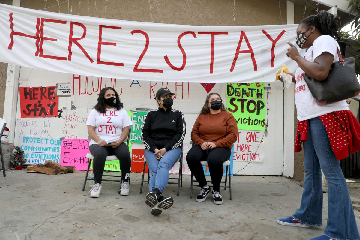 Tenants display a banner reading "HERE TO STAY" during a protest