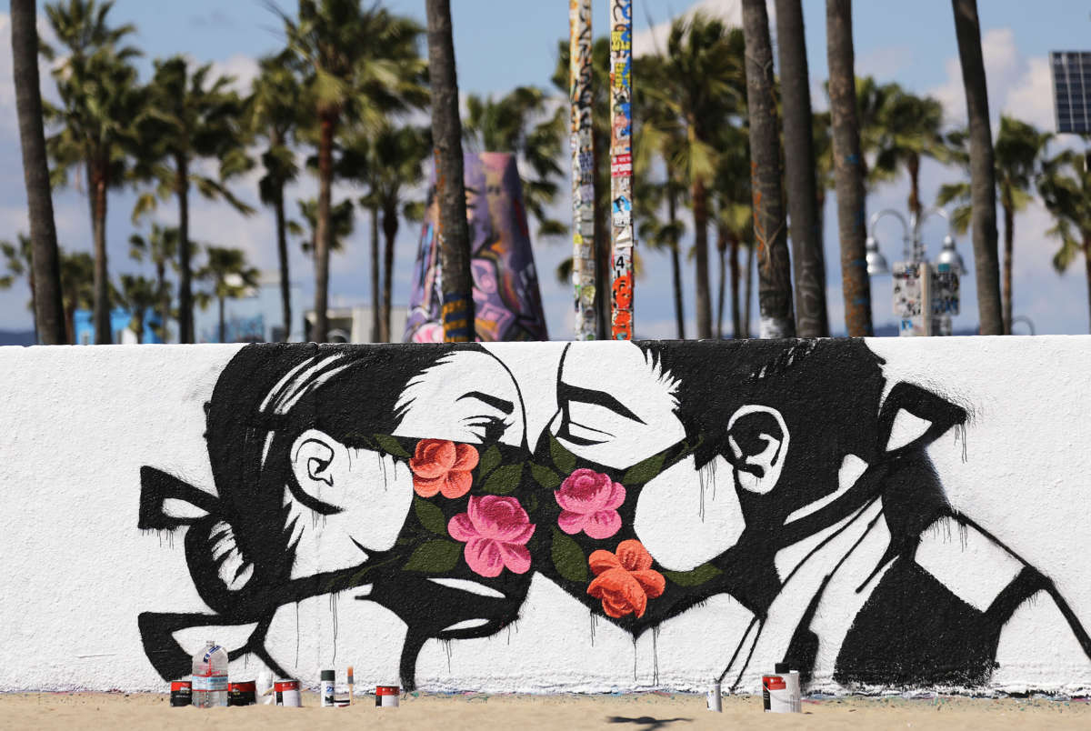 Two comrades kiss eachother through their flowered masks in a mural