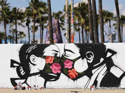 Two comrades kiss eachother through their flowered masks in a mural