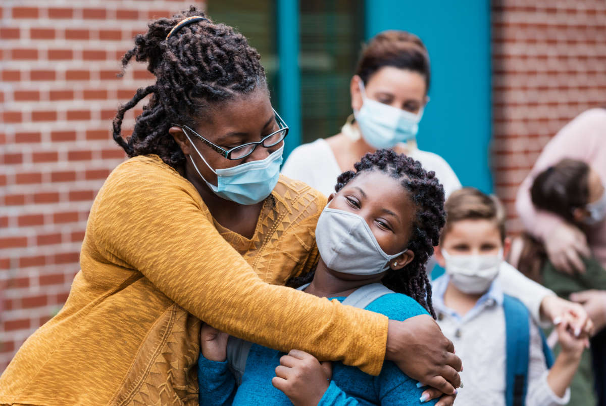 Mother and child embrace wearing facemasks