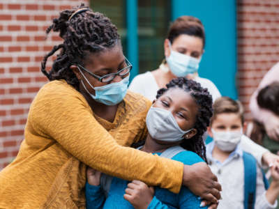 Mother and child embrace wearing facemasks